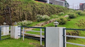 Una entrada protegida por una reja con una escalera de piedra que sube una colina cubierta de césped.