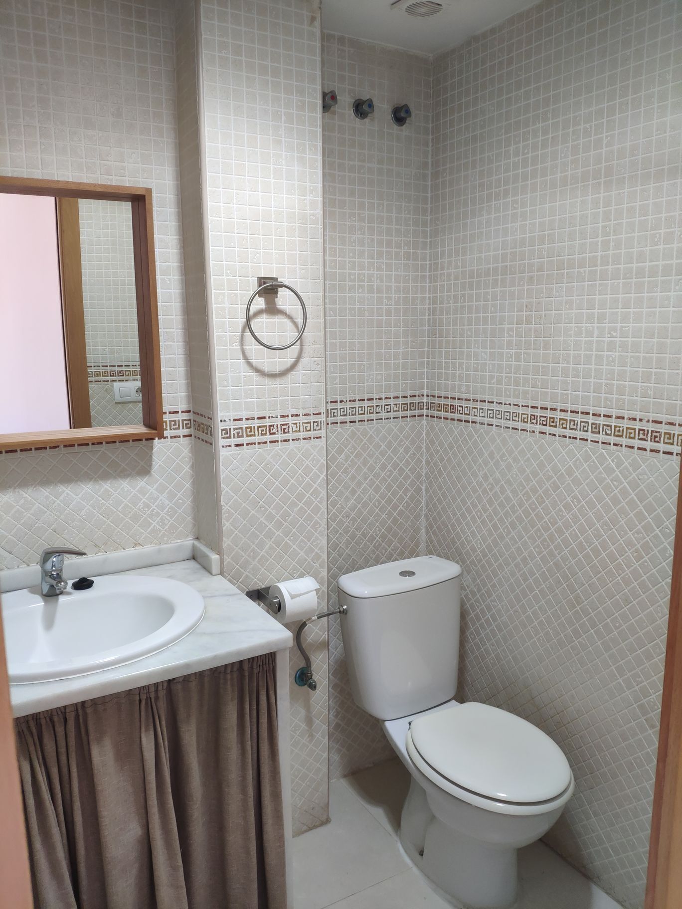 Un baño con lavamanos, inodoro y espejo.