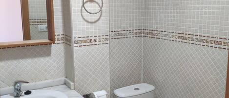 Un baño con lavamanos, inodoro y espejo.