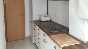A compact kitchen with a white refrigerator, a toaster, a stove, and a wooden countertop.