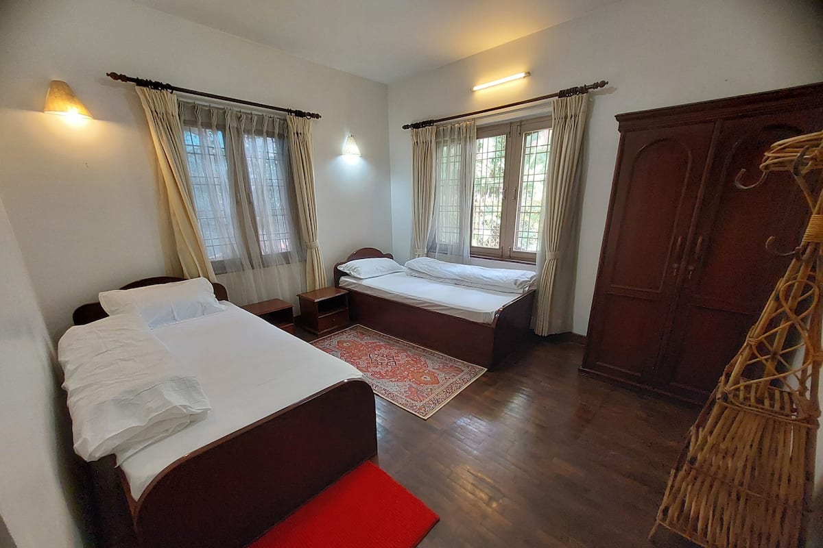 A bedroom with two beds, a wardrobe, and a red bench.