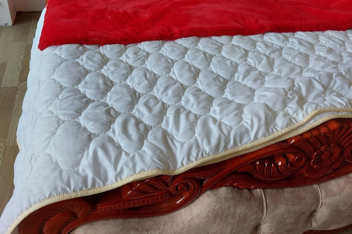 A bed with a red headboard, white bedding, and a red throw blanket.