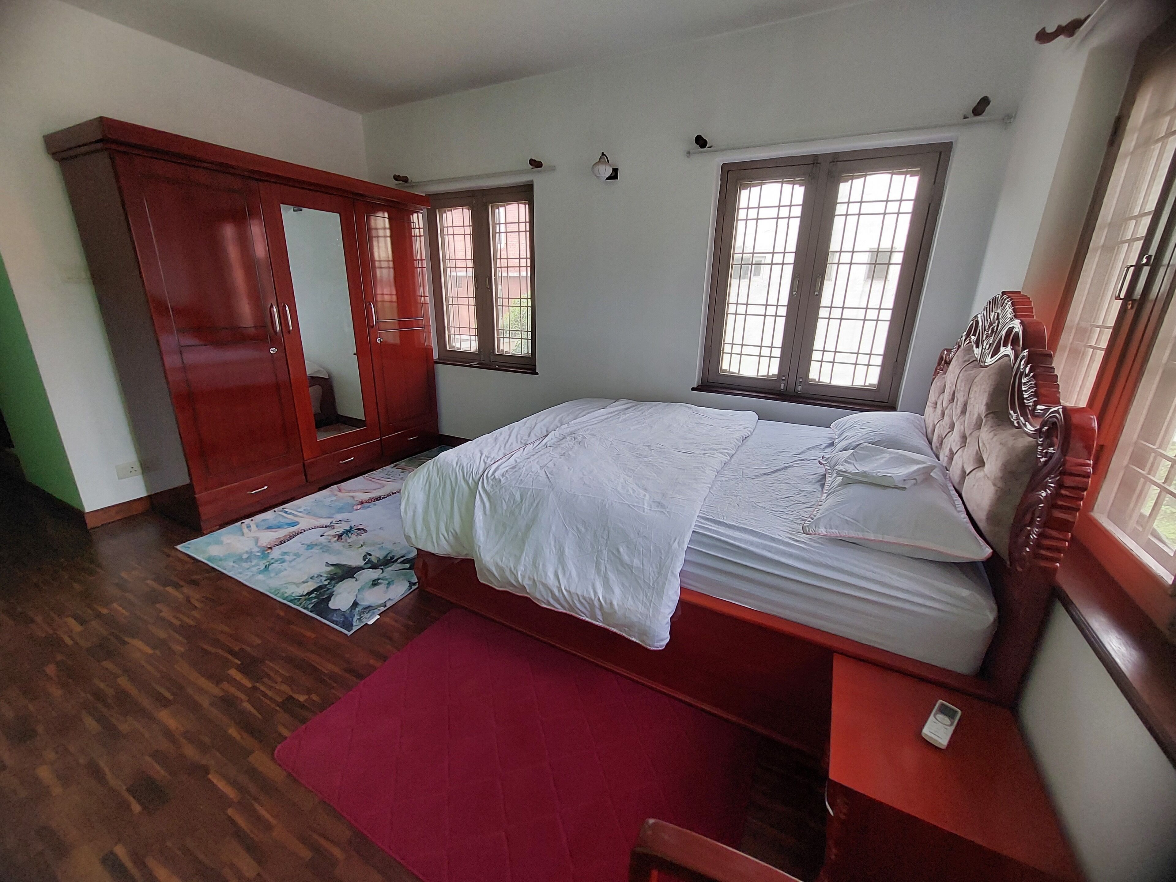 Un dormitorio con cama, armario, espejo y ventana.