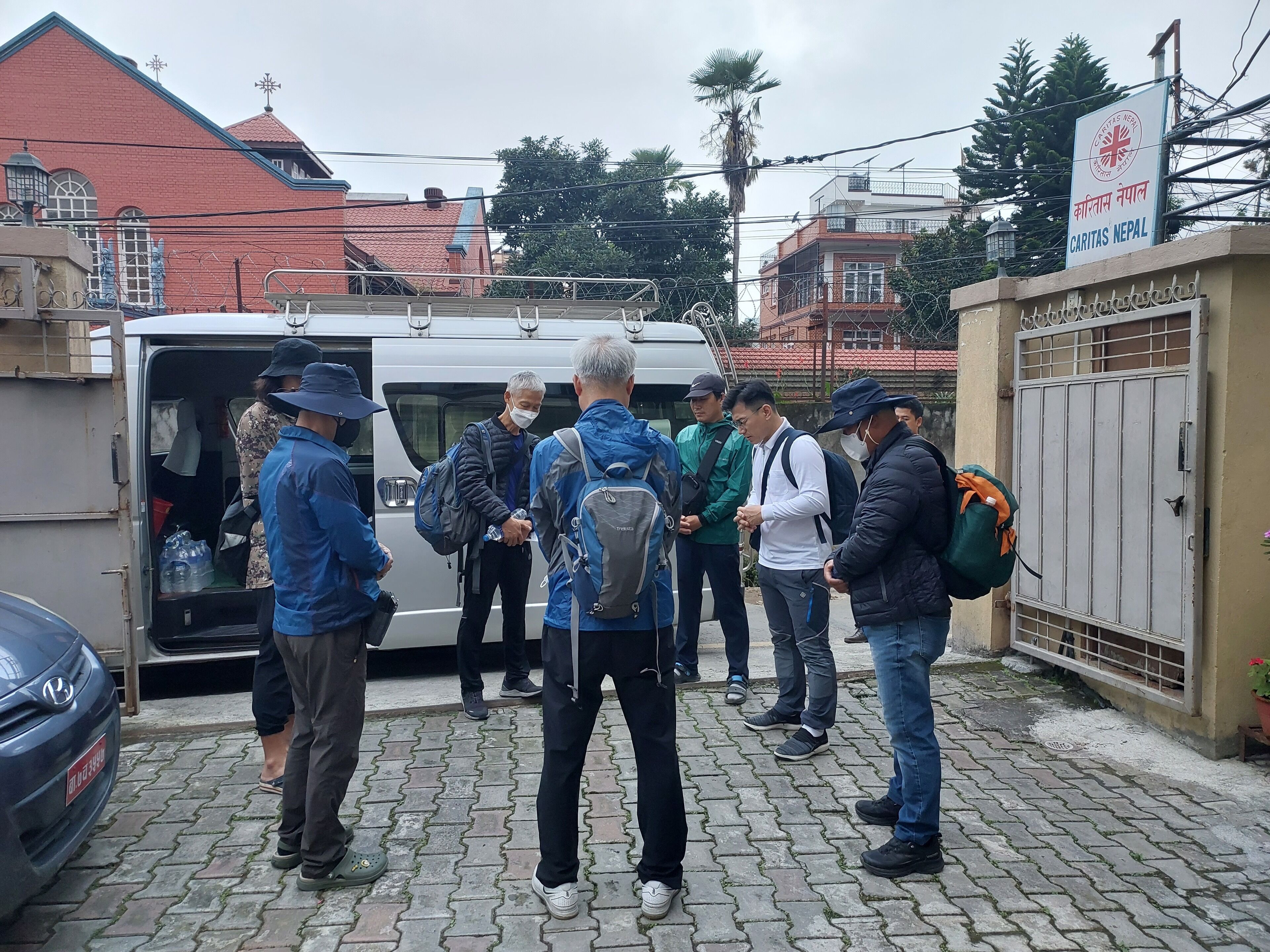 Un grup de persones al davant d'un vehicle amb un cartell que diu 'CARITAS NEPAL'.