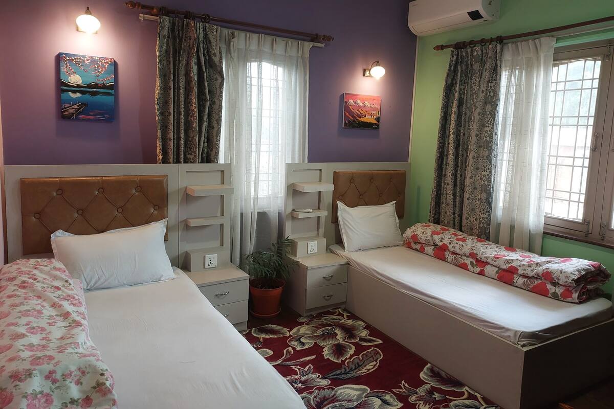 A hotel room with two beds, a potted plant, and artwork on the walls.