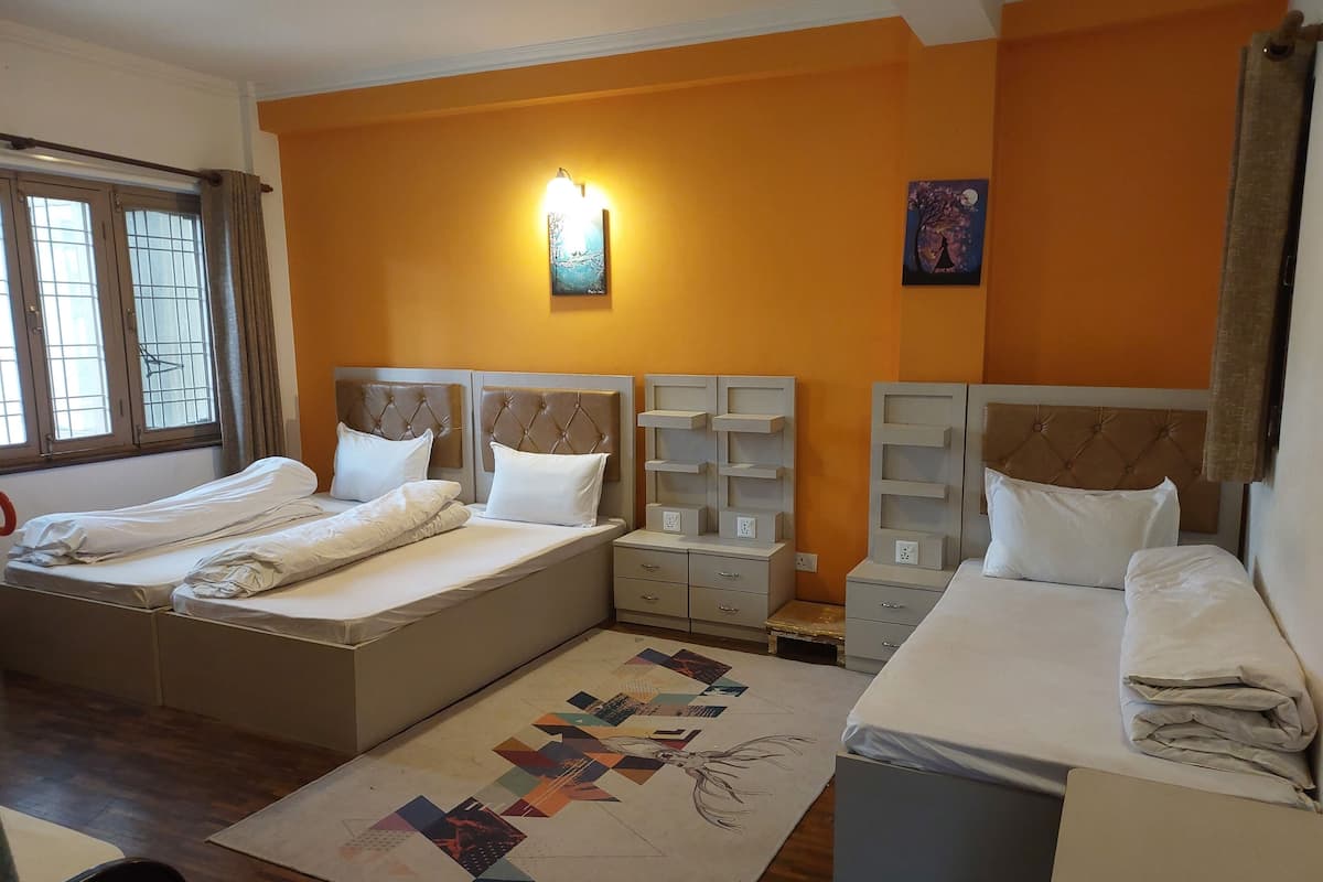 A hotel room with two beds, a nightstand, a wall-mounted lamp, and a painting.