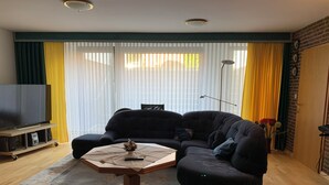 Ein Wohnzimmer mit Ecksofa, Couchtisch und Fernseher auf einem Schrank.