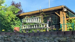 Ein Gebäude mit Holzkonstruktion, Metallgeländer und einer Steinmauer davor.