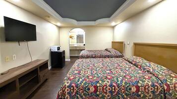Una habitación de hotel con una cama grande, un televisor montado en la pared, un escritorio pequeño y un espejo.