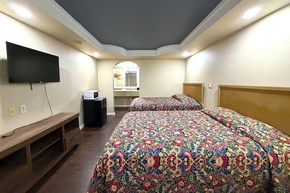 A hotel room with a large bed, a TV mounted on the wall, a small desk, and a mirror. - Budget Inn By Oyo Corpus Christi Beach (Portland)