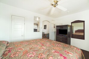 A bedroom with a bed, a ceiling fan, a dresser, a TV, and a mirror. - Budget Inn By Oyo Corpus Christi Beach (Portland)