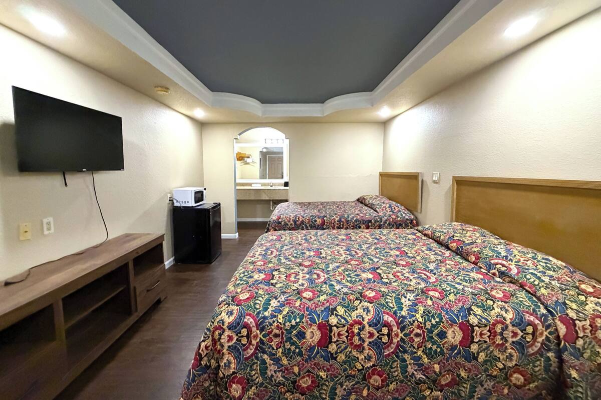 A hotel room with a large bed, a TV mounted on the wall, a small desk, and a mirror.