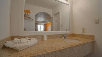 A bathroom with a granite countertop, a sink, a mirror, and a towel rack.