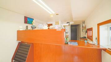A wooden reception desk with a staircase leading to an upper level. A television is mounted on the wall above the desk.
