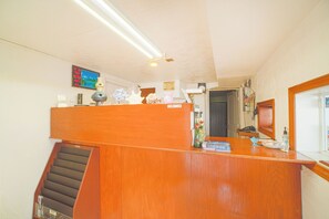 A wooden reception desk with a staircase leading to an upper level. A television is mounted on the wall above the desk. - Budget Inn By Oyo Corpus Christi Beach (Portland)