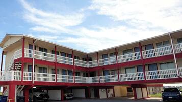 Un motel de varios pisos con un patio central, balcones y una zona de estacionamiento.