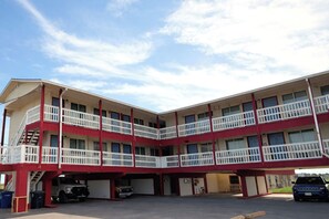 A multi-story motel with a central courtyard, balconies, and a parking area. - Budget Inn By Oyo Corpus Christi Beach (Portland)