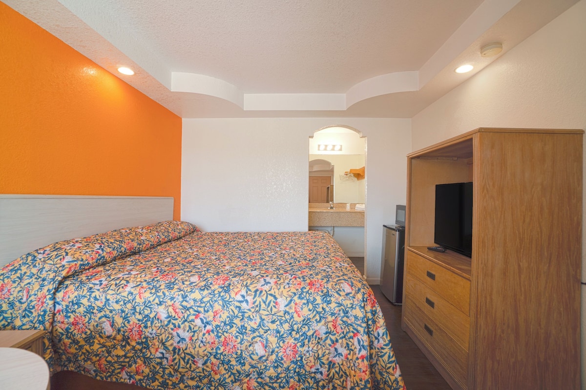 A bedroom with a bed, a TV, and a wooden wardrobe.