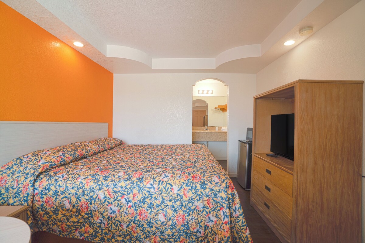 A bedroom with a bed, a TV, and a wooden wardrobe.
