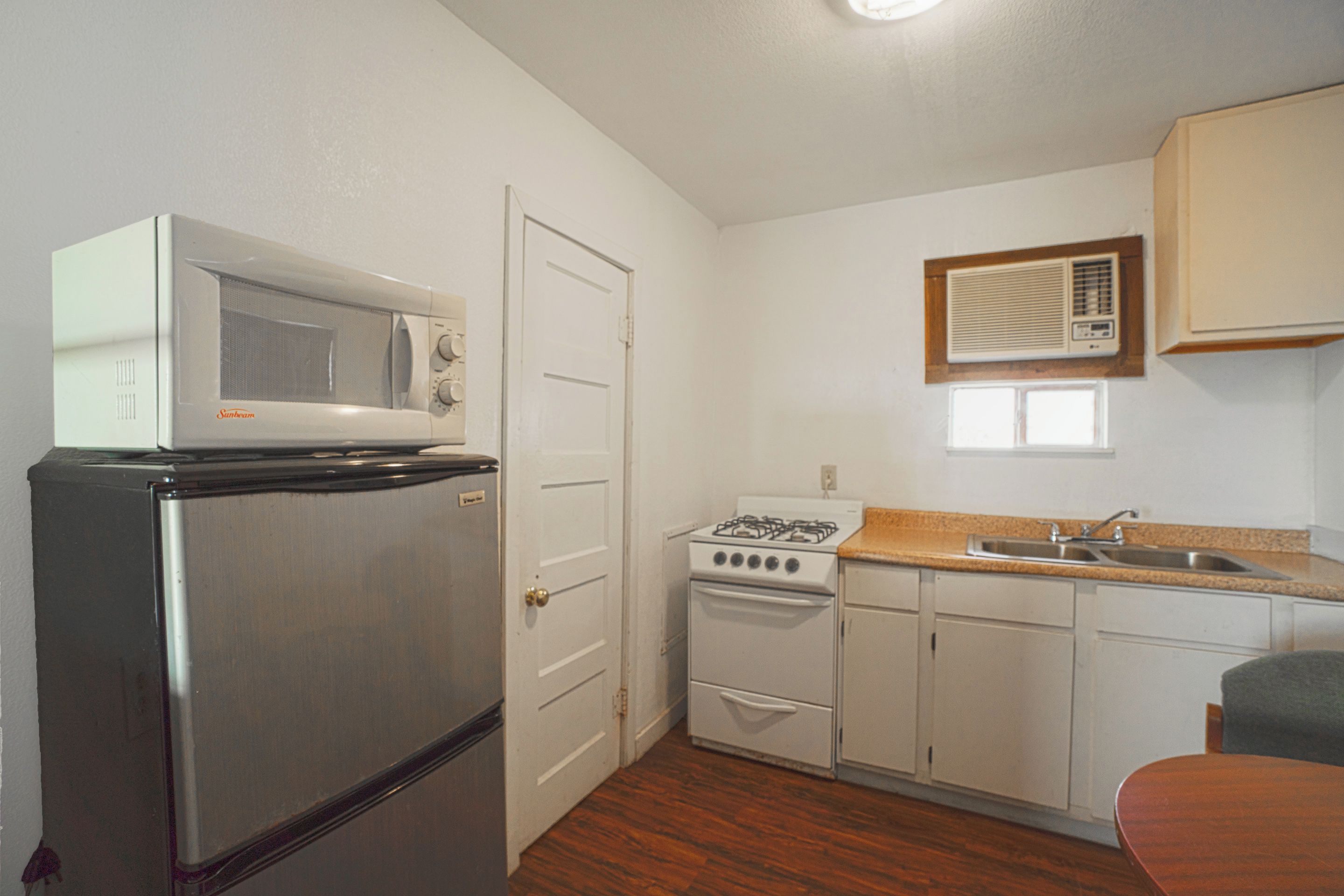 A compact kitchen with a refrigerator, microwave, stove, and sink.