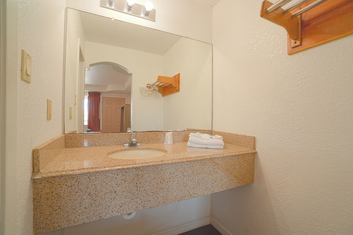 A bathroom with a granite countertop sink, a mirror, and a towel rack.