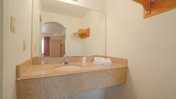 A bathroom with a granite countertop sink, a mirror, and a towel rack.