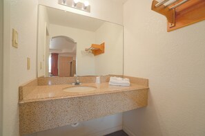 A bathroom with a granite countertop sink, a mirror, and a towel rack. - Budget Inn By Oyo Corpus Christi Beach (Portland)