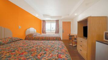 A bedroom with two beds, a wooden wardrobe, a television, and a window with curtains.