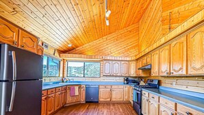 Una cocina con armarios de madera, un refrigerador, un lavavajillas y una estufa.