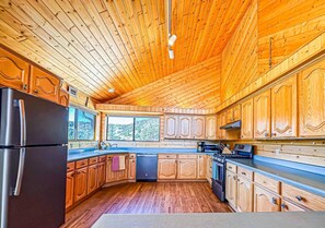 A kitchen with wooden cabinets, a refrigerator, a dishwasher, and a stove. - Lakeview Lodge at Panguitch Lake (Panguitch)