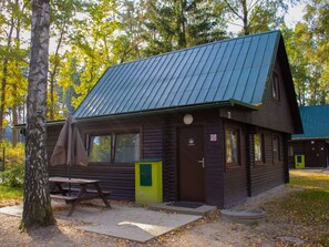 A cabin with a sloped roof, a picnic table, and a door with a no smoking sign.