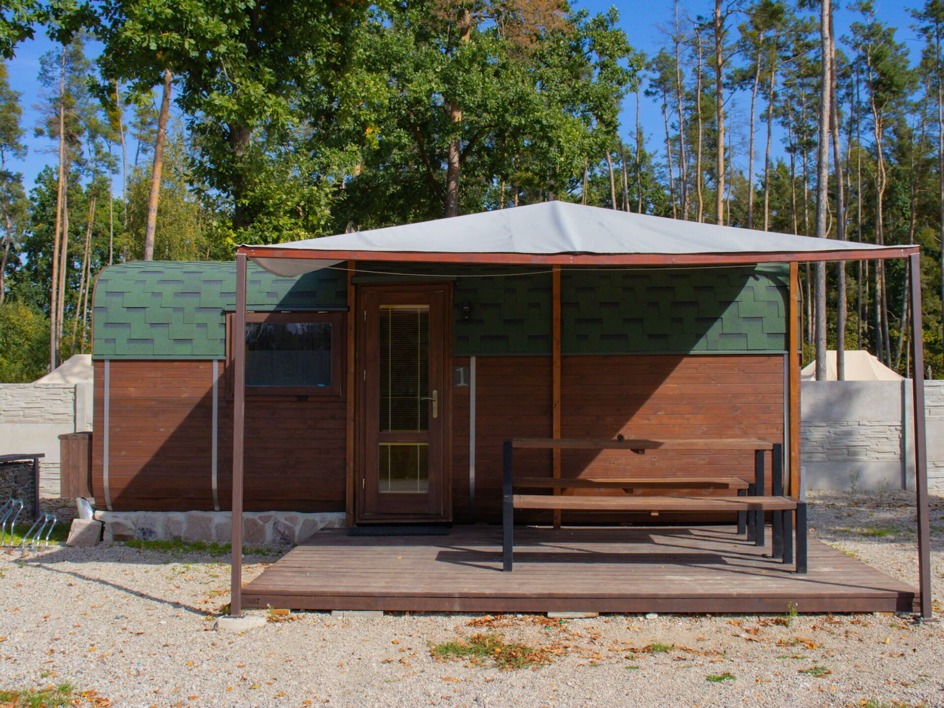Una piccola casetta di legno con veranda coperta e una panca.