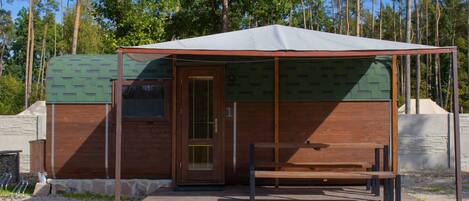 Una piccola casetta di legno con veranda coperta e una panca.