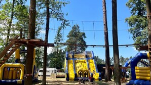 Ein Spielplatz im Freien mit Hüpfburgen und einer hölzernen Kletterkonstruktion.