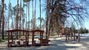 Ein Spielplatz mit Holzkonstruktionen und Bänken in einem bewaldeten Gebiet.