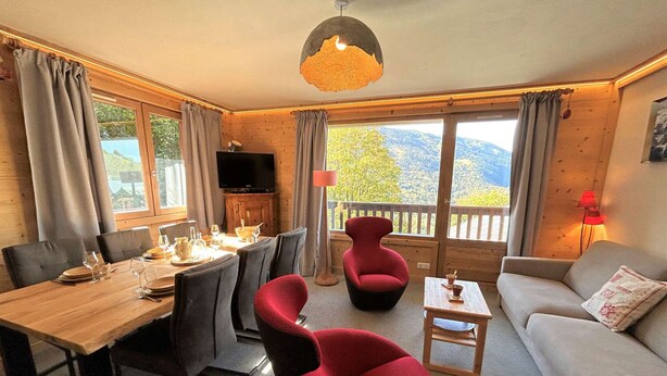 Ein gemütliches Wohnzimmer mit Essbereich, einem roten Sessel, einer Couch und einem Fernseher.