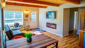 A spacious living room with a wooden ceiling, a fireplace, a television, and a seating area with a couch and chairs.