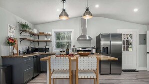 A modern kitchen with a central island, stainless steel appliances, and pendant lighting. - Hummingbird Haus: Sleeps 12 with Hot Tub (Fredericksburg)