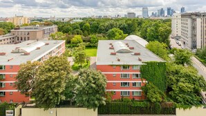 Ein mehrstöckiges Gebäude mit roter Fassade und Bäumen im Vordergrund.