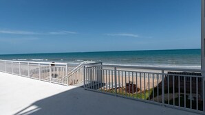 A balcony with a white railing overlooking a beach. - Oceanfront Updated Condo - Direct Beach Access! (Satellite Beach)