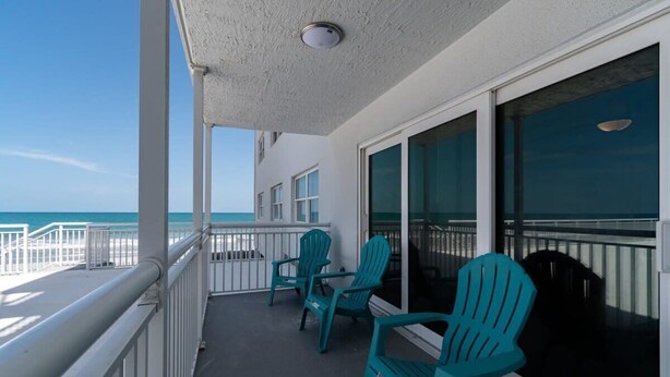 A balcony with a view of the ocean, equipped with a railing and two chairs. - Oceanfront Updated Condo - Direct Beach Access! (Satellite Beach)