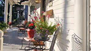 A covered porch with a rocking chair, potted plants, and outdoor lighting. - Spa Tub, Historic B & B, Get Spoiled! (Eureka Springs)