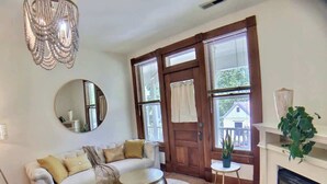 A living room with a white sofa, a round coffee table, a fireplace, and a large window with blinds. - 2 Bedroom Suite in Historic B&B, Breakfast Include (Eureka Springs)