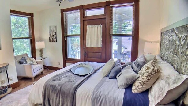 A bedroom with a large bed, a chair, a lamp, and a door with windows. - 2 Bedroom Suite in Historic B&B, Breakfast Include (Eureka Springs)