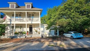 Une maison à deux étages avec un porche, un drapeau et une voiture garée dans l’allée.