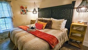 Une chambre à coucher avec un lit, une table de chevet, une fenêtre avec des rideaux et une lampe fixée au mur.