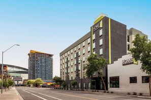 A hotel with a modern design, featuring a prominent 'HOME' sign, a large glass facade, and a street view with a clear sky. - Home2 Suites by Hilton Phoenix Downtown (Phoenix)