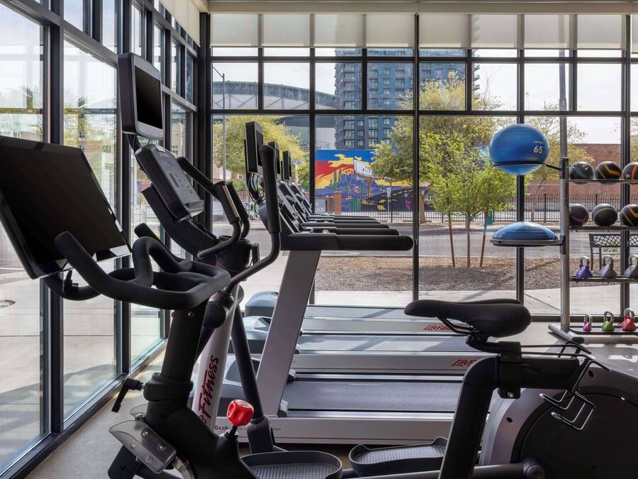 A gym with stationary bikes, treadmills, and a weight rack.