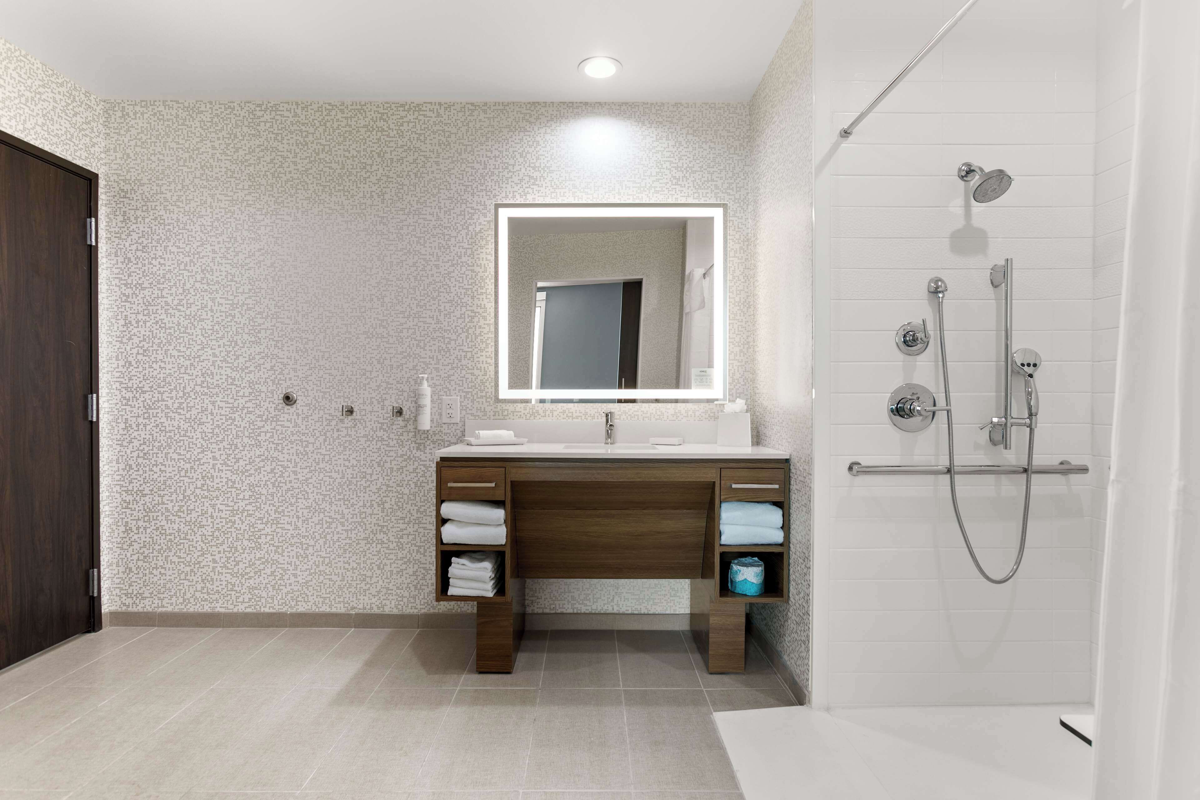 Un baño moderno con tocador de madera, un espejo grande y cabina de ducha.