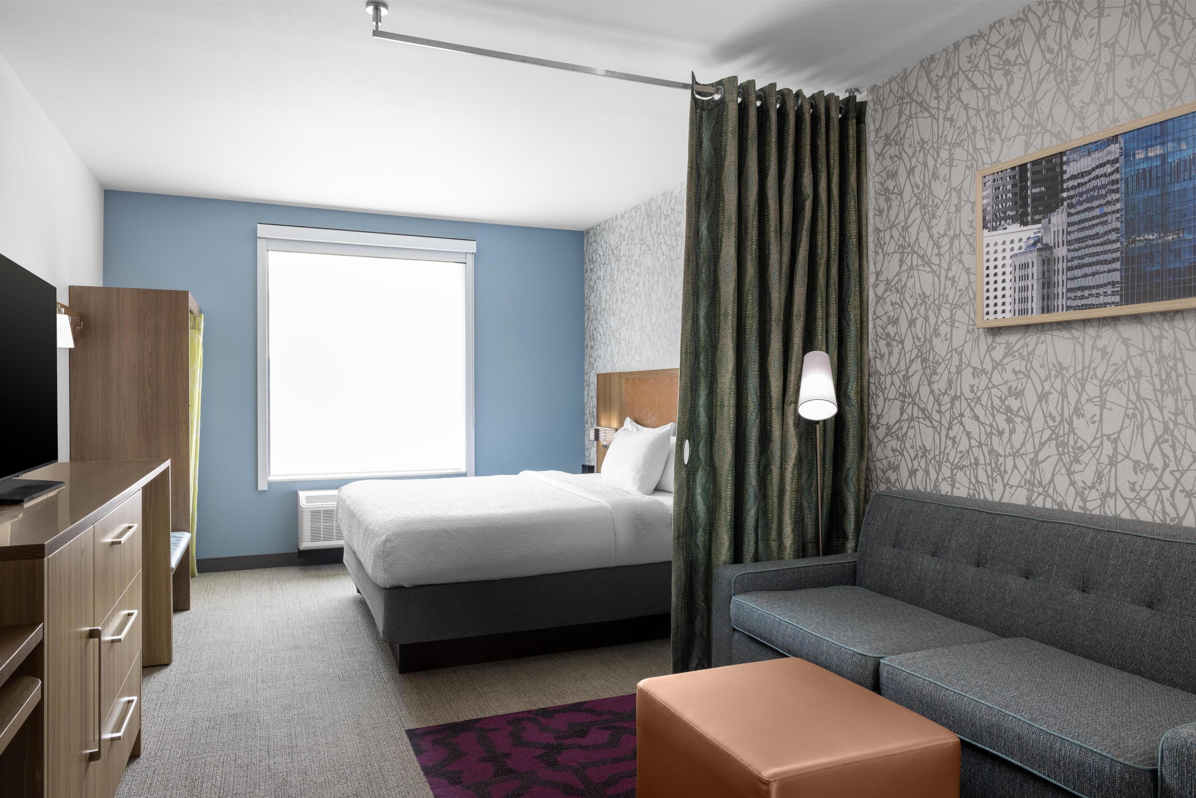 Una habitación de hotel con cama, sofá, escritorio y televisor.